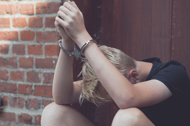 Juvenile under arrest with hands cuffed